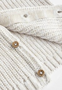 Strickpullover in hellbeige mit horizontaler Rippstruktur, ausgestattet mit einem Holzknopf und einem umgeschlagenen Kragen mit einer Schlaufen-Details.