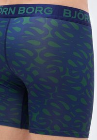 Μπόξερ briefs σε μπλε με πράσινο αφηρημένο σχέδιο. Διαθέτουν ελαστική μέση με το κείμενο "BJÖRN BORG". Λείο, ελαστικό ύφασμα.