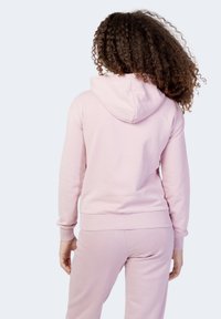 Felpa rosa realizzata in tessuto morbido con tasca a marsupio, polsini e orlo ribattuti. Presenta un cappuccio con coulisse, vista dal retro.