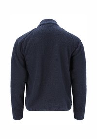 Merimetsän fleecetakki, pehmeä materiaali, korkea kaulus, pitkät hihat ja rento istuvuus, jossa on minimalistinen muotoilu ilman näkyviä kiinnityksiä.