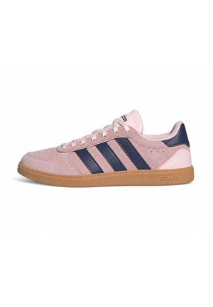 Sneaker Adidas a profilo basso in suede rosa chiaro con strisce blu scuro, suola in gomma, lacci e tallone e linguetta marchiati.