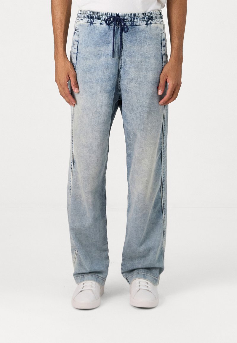 Απαλά μπλε τζιν jogger παντελόνια με κορδόνι στη μέση, πλαϊνές τσέπες και άνετη εφαρμογή, με ξεπλυμένη όψη και ίσιες γραμμές.
