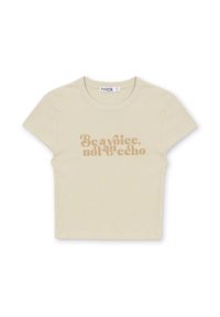 Camiseta corta beige de tejido acanalado con mangas cortas y cuello redondo; texto impreso en un marrón claro contrastante: "Sé una voz, no un eco."