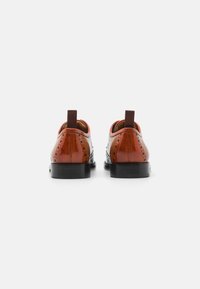Brown leather shoes with a round toe, brogue detailing, and elastic pull tabs. Features a black rubber sole and polished finish.