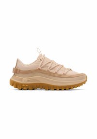 Beiger Sneaker mit niedrigem Schaft, dicker, strukturierter Kautschuksohle, überkreuzten Schnürsenkeln und Zuglasche an der Ferse, für den Außeneinsatz konzipiert.