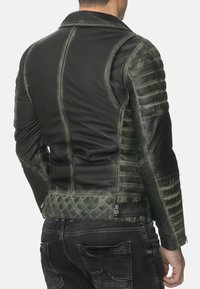 Giacca in pelle nera e verde con motivo trapuntato sulla parte bassa della schiena e sulle maniche, con colletto strutturato e design aderente.