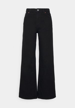 Jean large noir taille haute avec fermeture à boutons, poches avant et arrière, présenté sur un fond gris clair uni.