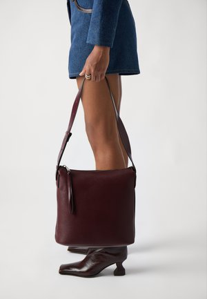 Burgundin värinen nahkainen olkalaukku, jossa on sileä pinta, vetoketjusuljenta ja säädettävä hihna; suorakulmainen muotoilu, jossa on minimalistinen design.