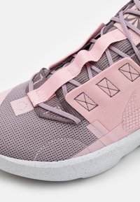 Zapatilla atlética en tonos rosa y gris, hecha de materiales de malla y ante, con superposiciones texturizadas, correas ajustables y una suela moteada.