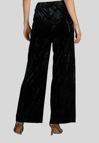 Zwarte fluwelen wijde broek met een gestructureerde afwerking en elastische tailleband, met een glad oppervlak en een vloeiende stijl.