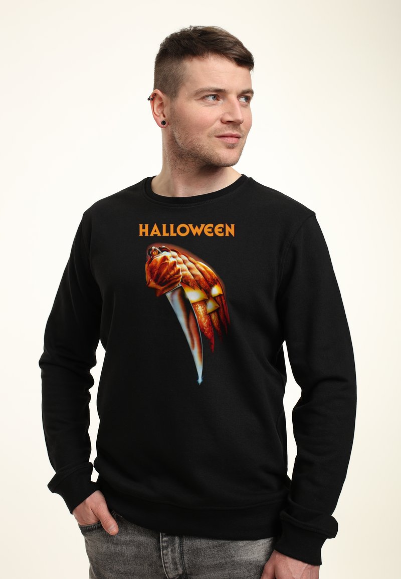 Felpa nera con una grafica di Halloween che rappresenta un coltello e una zucca con una mano, presentata in colori vivaci e dettagli intricati.