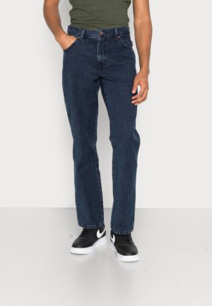 Jeans dritti blu scuro con design classico a cinque tasche, con cuciture sottili e una vita solida. Indossati con sneakers nere.