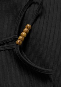 Μαύρος ριγωτός ύφασμα με υφασμάτινο σχέδιο, διαθέτοντας μία λουρίδα με βρόχο και τέσσερις στρογγυλές ξύλινες χάντρες σε χρυσό-καφέ χρώμα.