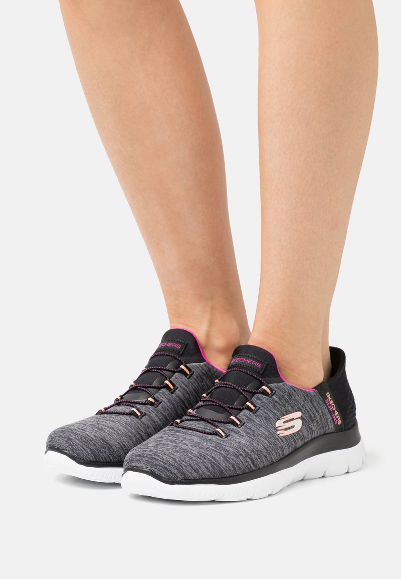 Grau-athletische Schuhe mit pinken Akzenten und schwarzem Rand. Überzug mit Struktur und flexibler weißer Sohle. Reflektierende Schnürsenkel und Logo vorhanden.
