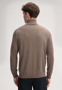 Brauner Rollkragenpullover aus feiner Strickware. Verfügt über lange Ärmel und eine figurbetonte Silhouette mit gerippten Bündchen und Saum.