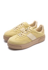 Zamszowe trampki w bladożółtym kolorze z teksturowanym wykończeniem. Posiadają kremowy tonowany pasek i beżową gumową podeszwę. Klasyczny design sznurowany.