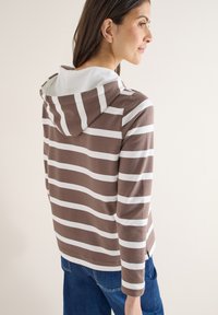 Hoodie rayé marron et blanc avec une poche kangourou à l'avant et un cordon de serrage. Manches longues, tissu doux et coupe décontractée.