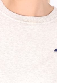 Vaalea harmaa huppari, jossa on teksturoitu, kirjava kangas. Varustettu ribbaatulla kaula-aukolla ja pienellä sinisellä logolla rintataskussa.