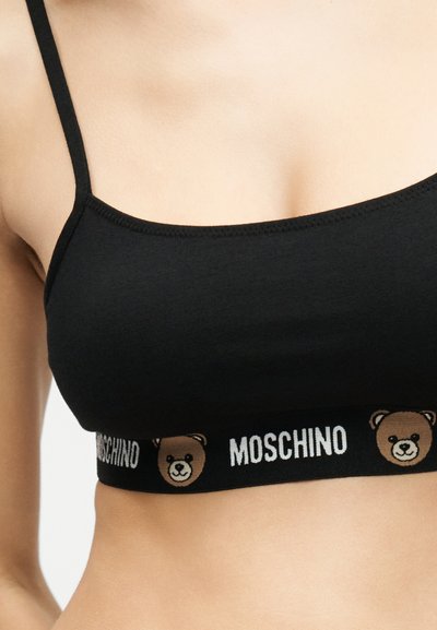 Μαύρο crop top με λεπτές τιράντες, ελαστική ταινία με το λογότυπο Moschino και καρτούν πρόσωπα αρκούδων, που φοριέται από άτομο.