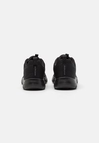 Black athletic shoes with a textured upper, featuring a soft material, a pull tab at the heel, and contrasting rubber soles.
