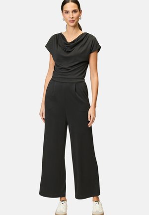 Combinaison noire avec un col drapé, des manches courtes et une coupe évasée. Fabriquée en tissu doux avec des poches latérales et une taille ajustée.