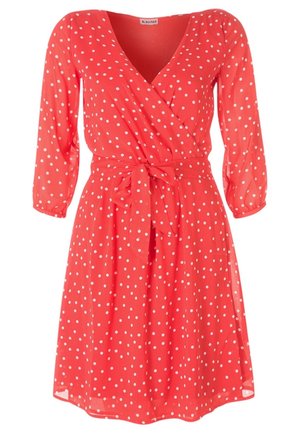 Koraalroze jurk tot op de knie met witte polkadots, driekwart mouwen, V-hals wikkelstijl en een gestrikte taille riem.