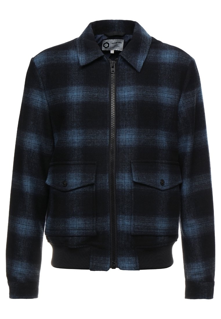 Giacca a quadri nera e blu con zip frontale, due tasche con patta sul petto e polsini e orlo a coste. Realizzata in tessuto intrecciato.