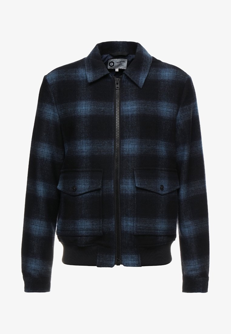 Giacca a quadri nera e blu con zip frontale, due tasche con patta sul petto e polsini e orlo a coste. Realizzata in tessuto intrecciato.