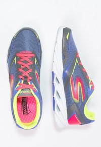 Chaussures de sport avec une tige en mesh bleu marine, des lacets rose vif, des accents jaune néon et une semelle intermédiaire blanche avec des découpes pour la respirabilité.