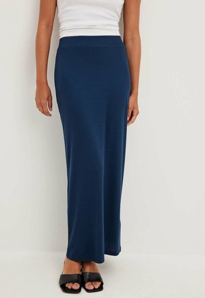 Marineblauwe geribde maxirok met een aangesloten tailleband, met een rechte silhouet. Gecombineerd met zwarte open-toe blockhak sandalen.