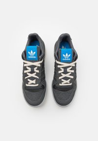 Gr�å Adidas sneakers med en texturerad överdel, krämfärgade snören, blå varumärkesetiketter och perforeringar på tåområdet.