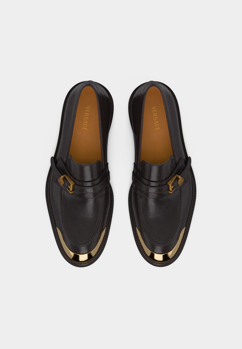 Mocassini neri in pelle con dettagli in metallo dorato sulle punte e fibbie laterali, con etichetta Versace all'interno.