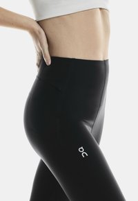 Black leggings with a smooth, stretchy fabric. Features a high waistband and a small logo on the side. No visible patterns or accents.