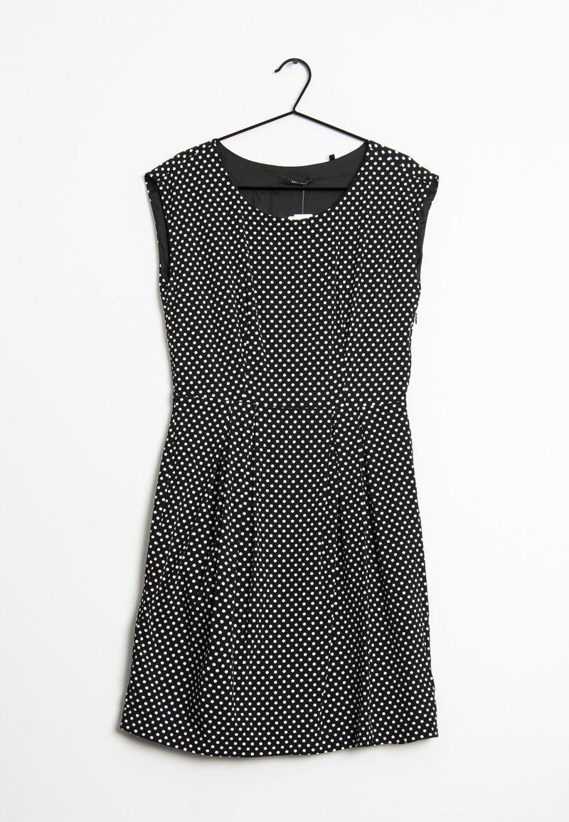 Robe noire sans manches à pois blancs, taille cintrée, jupe plissée, suspendue sur un cintre noir sur fond blanc.