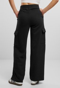 Schwarze Cargo-Hosen aus weichem Stoff, mit lockerer Passform, elastischem Bund und seitlichen Taschen zur Aufbewahrung.