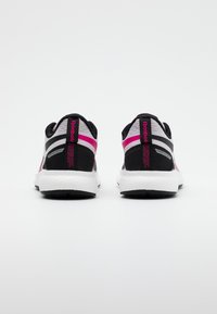 Ett par svarta, vita och rosa Reebok löparskor sedd från hälen, som visar "Floatride Energy"-logotypen på en vit bakgrund.