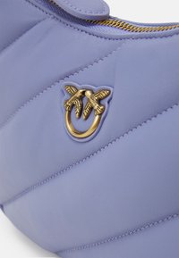 Borsa in pelle viola con texture trapuntata, con dettaglio in metallo dorato a forma di foglie di palma. Chiusura con cerniera lungo la parte superiore.