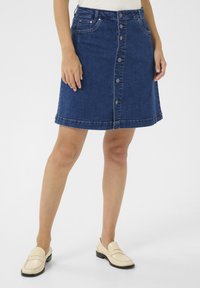 Jeanskjol med knapp fram, med två framfickor, en figurnära midja och en fåll som slutar ovanför knäet, i en medelblå tvätt.