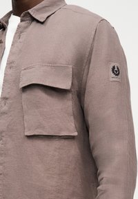 Τοπα πουκάμισο με μακριά μανίκια, μεγάλο μπροστινό τσέπη με πτερύγιο και μαύρο λογότυπο στη πάνω μανίκι.