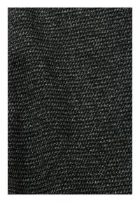 Detailní záběr na texturovanou tmavě šedou a černou tkaninu z tweedu s jemným kostkovaným vzorem.