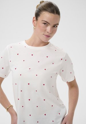 T-shirt en coton blanc à manches courtes, avec un motif dispersé de petits cœurs rouges. Encolure ronde, coupe décontractée, texture lisse.