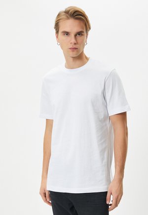 Hvid bomulls t-shirt med rund hals og korte ærmer, der har en glat tekstur og en afslappet pasform. Ingen mønstre eller detaljer synlige.