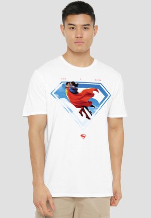 Man wearing white t-shirt with graphic of flying Lois and Clark inside a blue diamond-shaped Superman emblem.