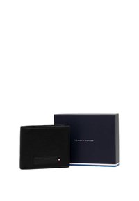 Portefeuille en cuir noir avec une finition texturée et une forme rectangulaire. Présente un patch de logo subtil et est livré dans une boîte bleue de marque.