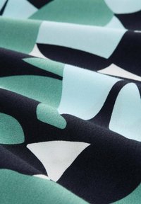 Stof met een geometrisch patroon in tinten teal, lichtblauw en zwart. De textuur is zacht met een gladde, fluweelachtige uitstraling.