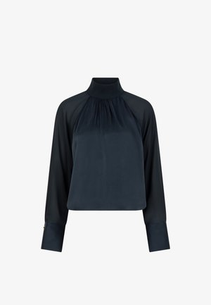 Navy blauwe blouse met een hoge hals, lange mouwen, zachte textuur en geplooide details aan de voorkant. Heeft op maat gemaakte manchetten en een cropped ontwerp.