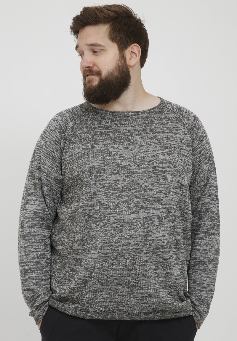 Grå og svart melert genser med rund hals, lange raglanermer og en avslappet passform. Myk tekstur og minimalistisk design.