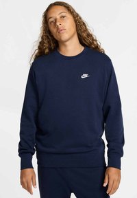 Felpa blu navy realizzata in tessuto morbido, con collo rotondo e maniche lunghe, con il logo Nike bianco sul petto.