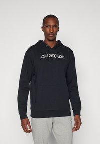 Felpa nera con tasca a canguro frontale, caratterizzata da un logo bianco. Realizzata in cotone morbido, presenta un cappuccio con cordino e polsini a coste.