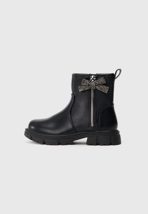 Zwarte leren enklaarsjes met een rits aan de zijkant en een studs strikaccent. Voorzien van een stevige rubberen zool en een gladde afwerking.